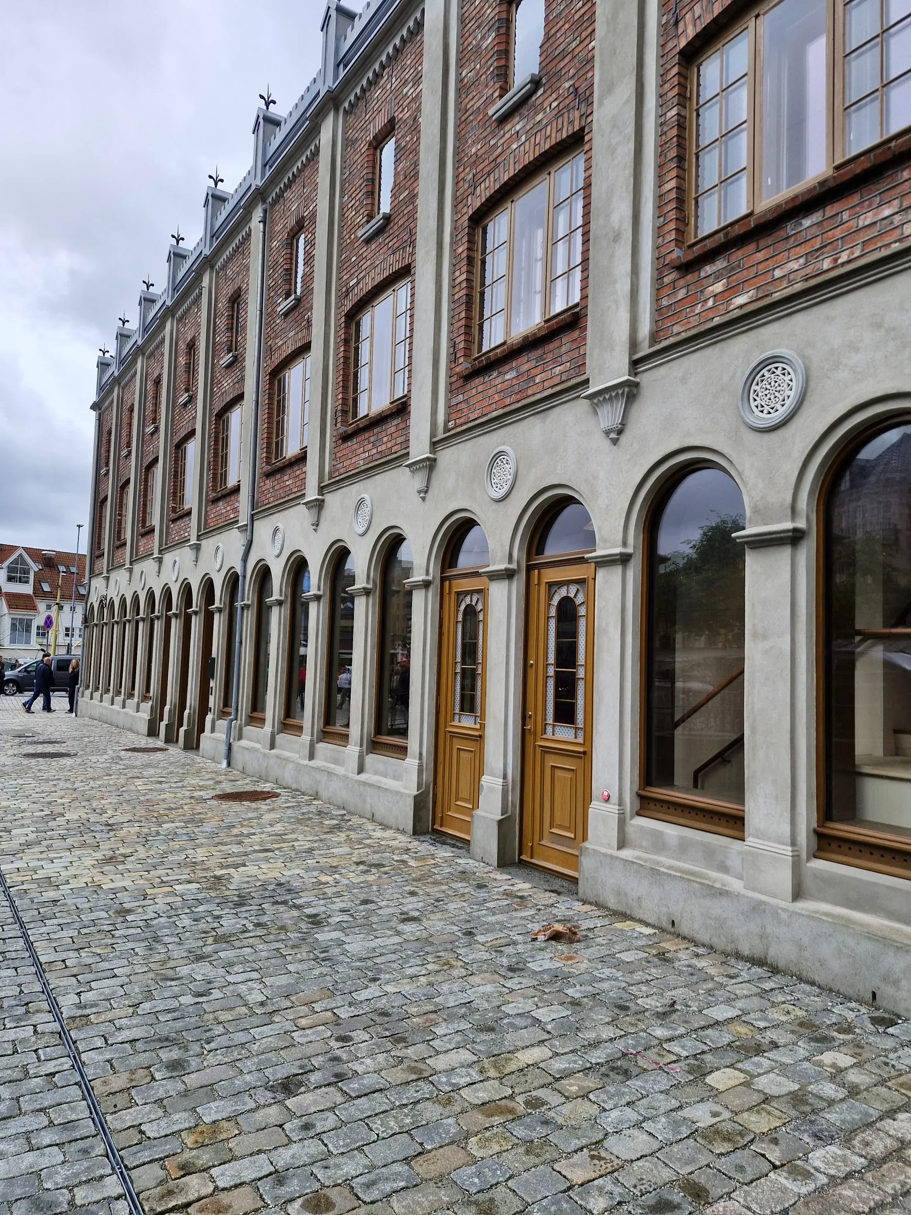 Rød teglfasade med pussede felt og buede vinduer.